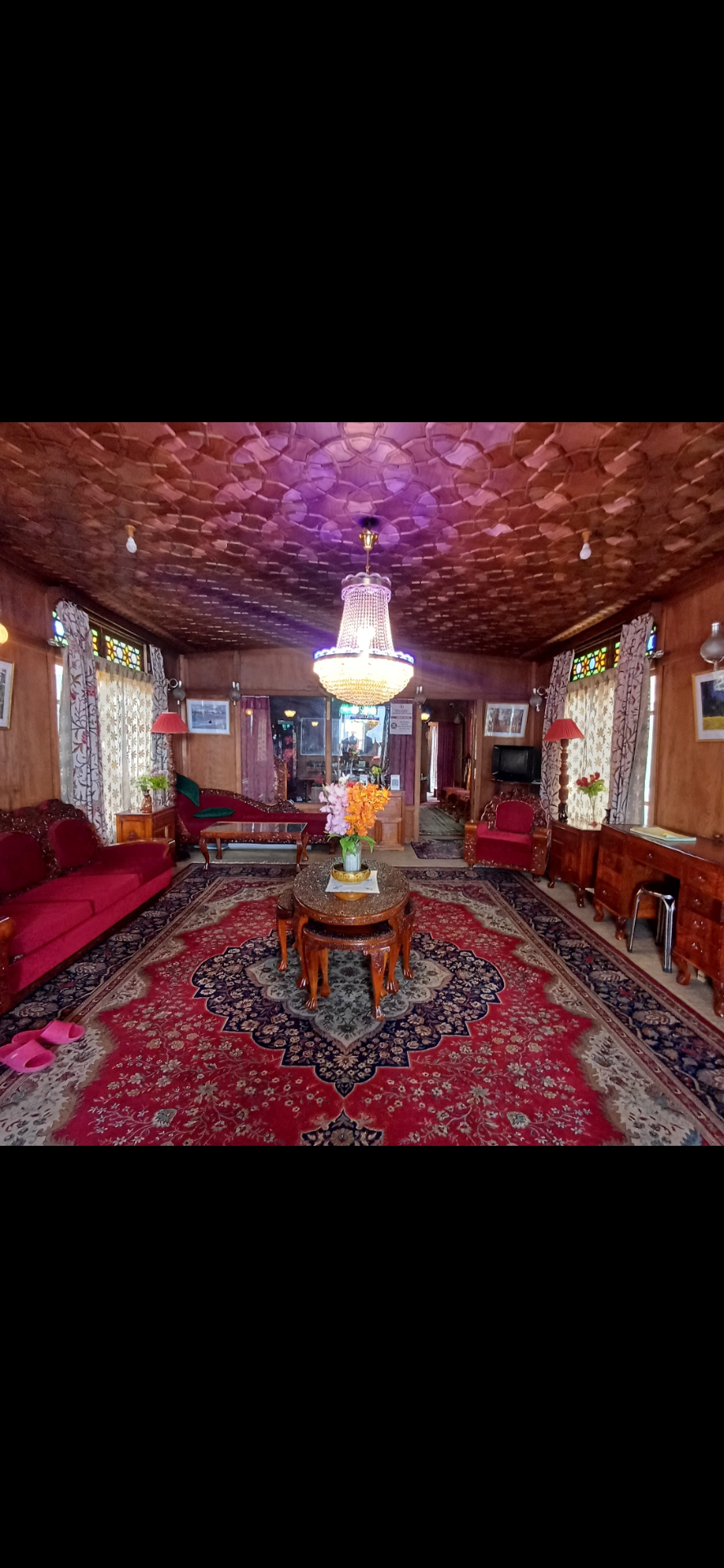 Houseboat lounge with traditional Kashmiri carpet and walnut ceiling